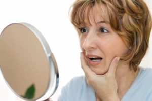 middle aged woman looking into mirror
