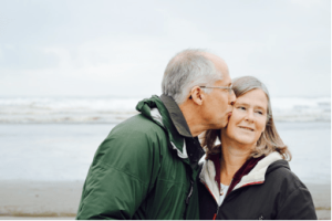Adventurous baby boomer kisses on the beach